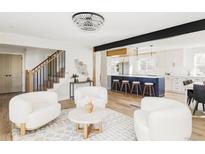 Bright open-concept living room showcasing modern lighting, a stylish kitchen, and a staircase to the second floor at 3100 S Holly Pl, Denver, CO 80222