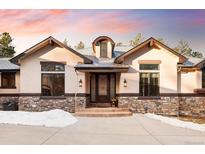 Charming home featuring a stone and stucco exterior with a welcoming front entrance and well-manicured landscaping at 8294 Wild Timber Dr, Franktown, CO 80116