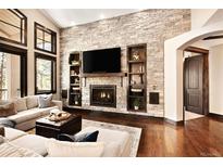 Cozy living room with stone fireplace, built-in shelving, and hardwood floors at 8294 Wild Timber Dr, Franktown, CO 80116