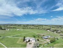 A picturesque aerial view of this home showcasing the large green field and a perimeter fence at 595 W Oak Hill Ln, Castle Rock, CO 80108