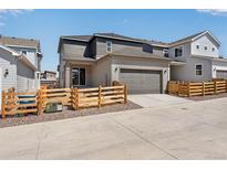 Charming two-story home with gray siding, a two-car garage, and a well-maintained front yard with a wood fence at 17844 E 107Th Pl, Commerce City, CO 80022