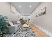Inviting living room featuring hardwood floors, a comfortable gray sofa, and seamless access to the dining area at 328 E Dakota Ave, Denver, CO 80209