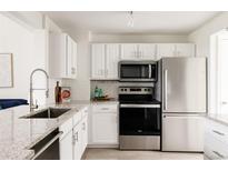 Bright kitchen featuring granite countertops, stainless steel appliances, and white cabinetry at 3026 W Prentice Ave # H, Littleton, CO 80123