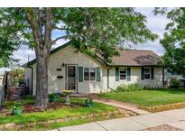 Charming home exterior with lush landscaping, lovely lawn, mature shade tree, and brick walkway to the front door at 334 S 7Th Ave, Brighton, CO 80601