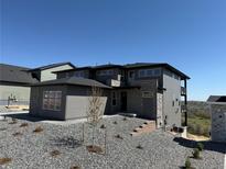 Modern two-story home featuring mixed stone and gray siding, set against a bright blue sky and minimal landscaping at 6036 Riesberg Ln, Castle Rock, CO 80104