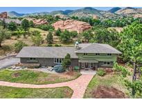 Stunning exterior view of the home, showcasing its brick and siding, lush landscaping, and mountain views at 6227 Colorow Dr, Morrison, CO 80465