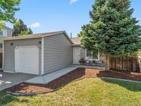 Charming home featuring a well-manicured lawn and an attached garage with a quaint outdoor seating area at 17411 E Layton Dr, Aurora, CO 80015