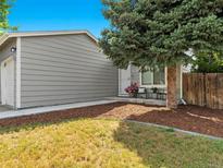 Charming single-Gathering home featuring a well-maintained lawn and a cozy front porch seating area with fresh flowers at 17411 E Layton Dr, Aurora, CO 80015