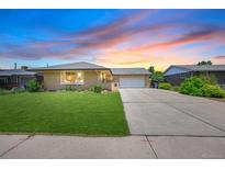 Charming single-story home featuring a well-maintained lawn and a spacious driveway leading to a two-car garage at 6987 E Wyoming Pl, Denver, CO 80224