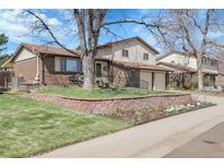 Charming two-story home with brick accents, landscaped yard, and mature trees under a beautiful blue sky at 4381 S Estes St, Littleton, CO 80123
