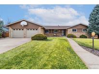 Ranch style home with brick and siding, two car garage, basketball hoop, and manicured lawn at 5819 W Milan Pl, Denver, CO 80235