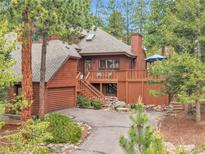 Beautiful home featuring wood exterior and charming deck with outdoor seating area at 29857 Park Village Dr, Evergreen, CO 80439