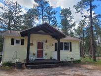 Charming cottage-style home with a welcoming front porch and beautifully maintained landscaping surrounded by mature trees at 36351 County Road 21, Elizabeth, CO 80107