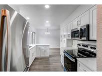 Kitchen with stainless appliances, modern countertops, and gray flooring next to dining area at 53 S Eagle Cir, Aurora, CO 80012