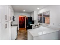 Bright kitchen features white cabinets, quartz countertops, wood floors, and stainless steel appliances at 53 S Eagle Cir, Aurora, CO 80012