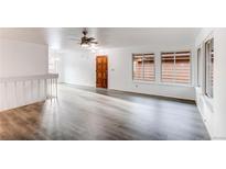 Bright, open living room featuring stylish gray floors, white walls, ceiling fan, and a classic wood front door at 53 S Eagle Cir, Aurora, CO 80012