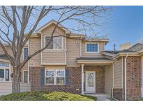 Inviting brick and tan two-story home with a well-maintained front yard and a charming covered entryway at 112 W Sterne Pkwy, Littleton, CO 80120