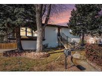 Charming single Gathering home with a brick facade, mature trees, and beautiful landscaping at 7077 Ammons St, Arvada, CO 80004