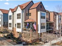 Charming brick and siding townhome with balcony, American and Colorado flags, and well-maintained landscaping at 439 S Reed Ct, Lakewood, CO 80226