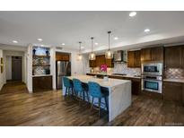 Modern kitchen featuring an island, stainless steel appliances, and stylish backsplash at 85 Rampart Way # 206, Denver, CO 80230