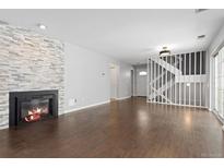 Bright living room with fireplace, wood floors, and staircase leading to the upper level at 2366 S Troy St, Aurora, CO 80014