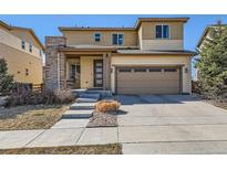 Tan two-story home with stone accent column and a two car garage at 10023 Uravan St, Commerce City, CO 80022