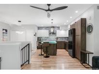 Modern kitchen featuring a large island with seating, stainless steel appliances, and hardwood floors at 3295 Blake St # 102, Denver, CO 80205