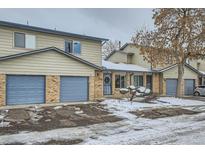 Tan brick townhome with blue garage doors and snowy landscaping at 5260 Garrison St # 6, Arvada, CO 80002