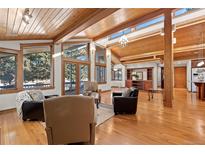 Bright living room features hardwood floors, wood ceiling beams and many windows offering plenty of natural light at 78 Fairway Ln, Littleton, CO 80123