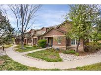 Charming townhome showcasing a manicured front yard, brick facade, and inviting walkway at 6476 Silver Mesa Dr # A, Highlands Ranch, CO 80130