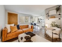 Cozy living room featuring a tufted leather sofa, stylish ottoman, and an open layout to the kitchen at 1349 Race St # 5, Denver, CO 80206