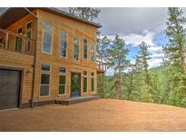 Stunning contemporary home exterior with wood siding, large windows, and a walkout balcony overlooking treed lot at 15175 Rainbow Dr, Sedalia, CO 80135