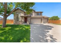 Charming two-story home featuring a well-manicured lawn and a three car garage on a sunny day at 12814 Forest Cir, Thornton, CO 80241
