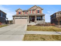 Charming two-story home with a well-manicured lawn, stone accents, and a two car garage at 23893 E Minnow Cir, Aurora, CO 80016