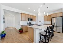 Bright kitchen featuring quartz counters, wood cabinets, and an island with breakfast bar seating at 18953 E 97Th Ave, Commerce City, CO 80022