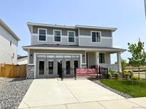 Charming two-story home with gray siding, large windows, covered porch, and well-maintained landscaping at 104 Wooten Ave, Brighton, CO 80601