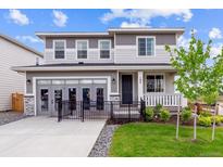 Charming two-story home with a landscaped yard, front porch and gray accent colors at 104 Wooten Ave, Brighton, CO 80601