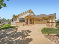 Inviting exterior with a two-car garage, a well-manicured lawn, and a long driveway at 7922 S Algonquian Way, Aurora, CO 80016