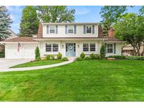 Charming two-story home featuring a lush green lawn, blue door, and lovely landscaping at 5061 S Florence Dr, Englewood, CO 80111