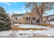 Charming home featuring a cozy front porch and mature trees at 6900 E 66Th Ave, Commerce City, CO 80022