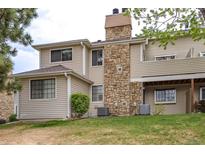 A multi-level home exterior with stone accents and light-colored siding, showcasing a well-maintained lawn at 12406 E Pacific Cir # D, Aurora, CO 80014