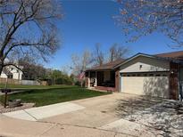 Charming single-story home features a well-manicured lawn, covered porch, and attached two-car garage at 10566 Canosa Ct, Denver, CO 80234