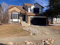 Two-story brick home with a white upper level, a black garage door, and a landscaped front yard at 20971 E 42Nd Ave, Denver, CO 80249