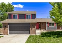 Home with a brick and siding exterior, a two-car garage, and vibrant landscaping, set against a blue sky at 6062 S Newport St, Centennial, CO 80111