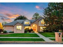Charming two-story brick home featuring a well-manicured lawn, mature trees, and inviting entrance at sunset at 2245 Ridgeview Way, Longmont, CO 80504