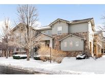 Two-story townhome with stone accents and snow-covered landscaping at 6723 S Winnipeg Cir # 104, Aurora, CO 80016