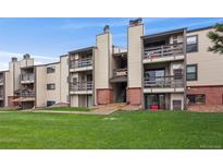 Multi-level condo building with balconies and a well-maintained lawn at 579 Wright St # 204, Lakewood, CO 80228
