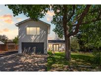 Charming home exterior with a spacious garage, well-maintained lawn, and mature trees providing shade and character at 6303 W Exposition Ave, Lakewood, CO 80226