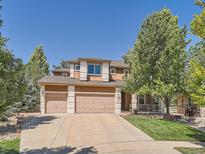 Charming two-story home features a three-car garage, well-manicured lawn, and mature shade tree at 13891 Muirfield Ct, Broomfield, CO 80023