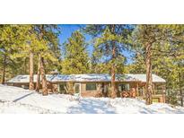 Charming single-story home featuring a snowy landscape and nestled among tall pine trees at 33477 Valley View Dr, Evergreen, CO 80439
